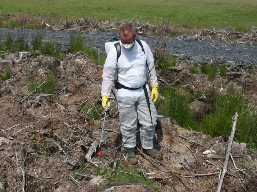 A man using Micron's handheld automated dosing knapsack sprayer - The AutoDos in a forestry setting