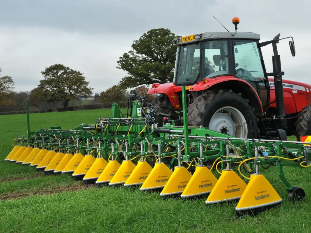 A Micron Varidome hooded band sprayer fitted to a tractor in a field